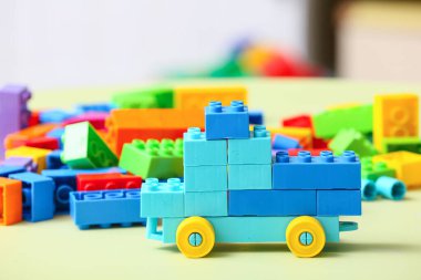 Toy car made of colorful plastic building blocks on beige table in children's room
