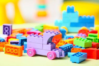 Toy car made of colorful plastic building blocks on beige table in children's room