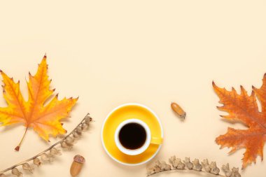 Cup of coffee with acorns, autumn leaves and dried henbane seed pods on beige background