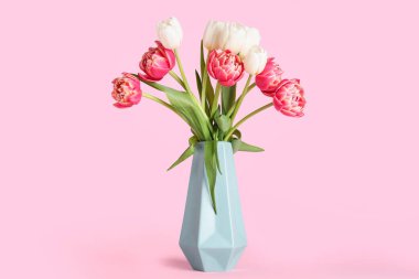 Vase with beautiful tulip flowers on pink background