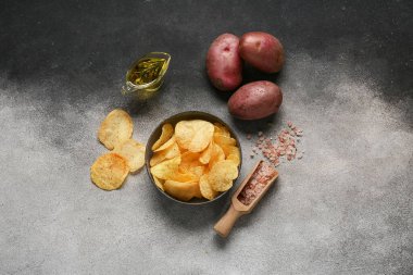 Lezzetli patates cipsi, deniz tuzu ve grunge arkaplanda yağlı bir tekne.