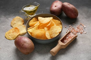 Lezzetli patates cipsi, deniz tuzu ve grunge arkaplanda yağlı bir tekne.