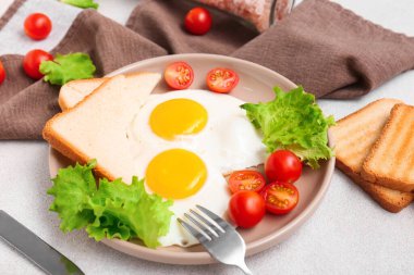 Hafif arka planda leziz yumurta, domates, marul ve kızarmış ekmek tabağı.