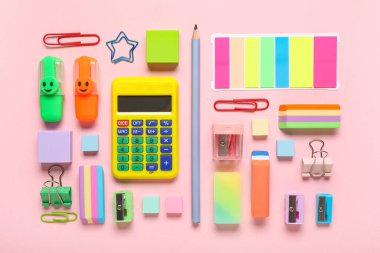 Pembe zemin üzerinde hesap makinesi ve kırtasiye malzemesi olan farklı silgi.