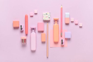 Different rubber erasers with markers, pencils, sharpeners and sticky note on purple background