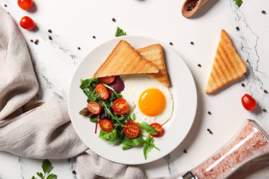 Lezzetli sahanda yumurta, salata karışımı, domates ve mermer arkaplanda tost.
