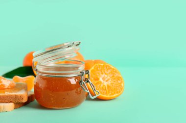 Turkuaz arka planda bir kavanoz tatlı mandalina reçeli