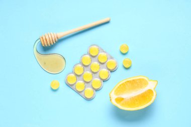 Öksürük damlaları mavi arka planda limon, ballı ve ballı.