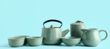Çaydanlık, fincanlar, kase ve sürahi mavi arka planda