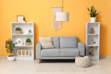 Modern oturma odası, şık gri kanepe ve asılı lamba.