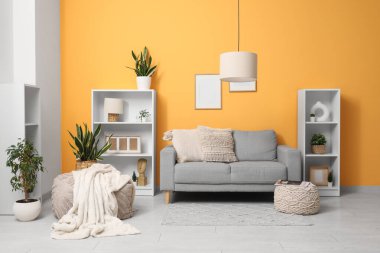 Modern oturma odası, şık gri kanepe ve asılı lamba.