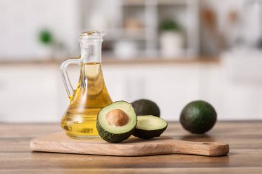 Bir sürahi taze yağ ve mutfak masasının üzerinde avokado ile kesme tahtası.