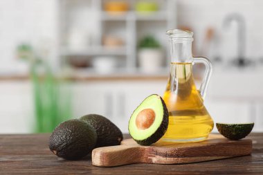 Bir sürahi taze yağ ve mutfak masasının üzerinde avokado ile kesme tahtası.