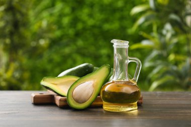 Bir sürahi taze yağ ve açık havada ahşap masa üzerinde avokado kesme tahtası.