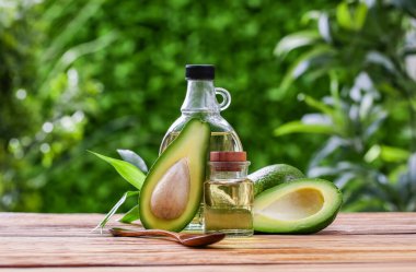 Dışarıdaki ahşap masada taze avokado yağı şişeleri.