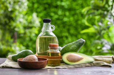 Dışarıdaki siyah ahşap masada taze avokado yağı şişeleri.