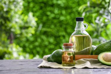 Dışarıdaki siyah ahşap masada taze avokado yağı şişeleri.