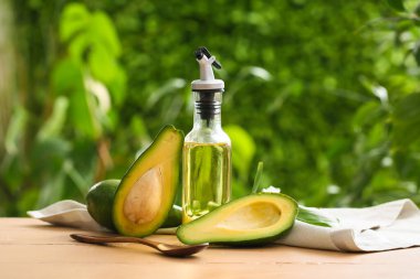 Dışarıdaki bej ahşap masada bir şişe taze avokado yağı.