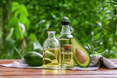 Dışarıdaki ahşap masada taze avokado yağı şişeleri.