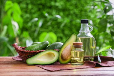 Dışarıdaki ahşap masa üzerinde avokado bulunan taze yağ ve hasır sepetler.