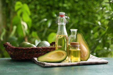 Yeşil masada avokado bulunan taze yağ ve hasır sepet.