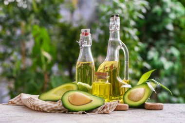 Dışarıdaki beyaz masada taze avokado yağı şişeleri.