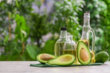 Dışarıdaki beyaz masada taze avokado yağı şişeleri.