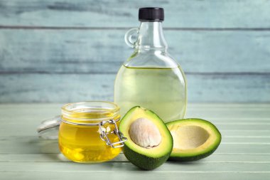 Taze avokado, şişe ve yağ dolu kavanoz renkli ahşap masa.