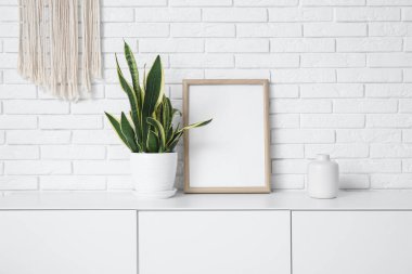 Beyaz tuğla duvarın yanında sandık ve çerçeve.