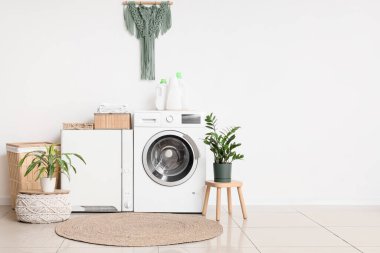 Çamaşır odasının içinde modern çamaşır makinesi ve çamaşır kurutma makinesi beyaz duvarın yanında.