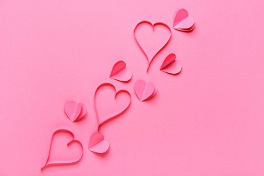 Pembe arka planda kağıtlardan yapılmış kalpler. Sevgililer Günü kutlaması