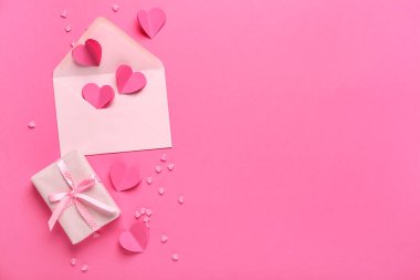 Zarflı kağıt kalpler ve pembe arka planda hediye kutusu. Sevgililer Günü kutlaması