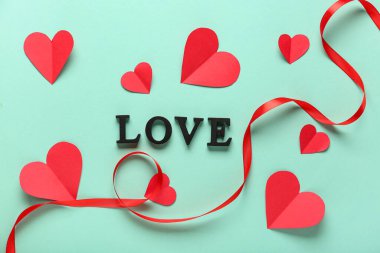 Kırmızı kağıt kalpli ve turkuaz arka planda kurdeleli mesaj. Sevgililer Günü kutlaması