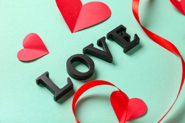 Kırmızı kağıt kalpli ve turkuaz arka planda kurdeleli mesaj aşkı, yakın plan. Sevgililer Günü kutlaması