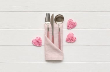 Sevgililer Günü için sofra takımı, dekoratif kalpler ve beyaz ahşap arka planda peçete.