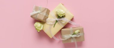 Pembe arka planda güzel beyaz güller olan hediye kutuları, üst manzara.