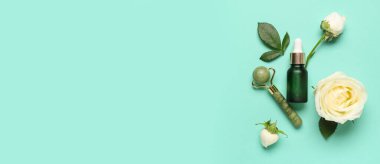 Güzel beyaz güller, bir şişe kozmetik ürün ve turkuaz arka planda masaj silindiri.