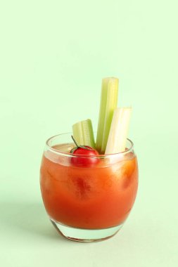 Yeşil arka planda kereviz ve domatesli bir bardak Bloody Mary.