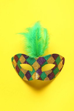 Sarı arka planda Mardi Gras kutlaması için tüylü parlak karnaval maskesi.