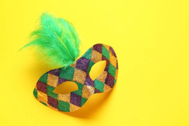 Sarı arka planda Mardi Gras kutlaması için tüylü parlak karnaval maskesi.