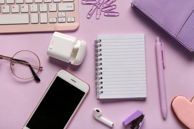 Not defteri, kulaklık ve eflatun kaplamalı telefon kompozisyonu. Üst görünüm