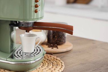 Mutfaktaki masada bir kavanoz fasulye ile modern yeşil kahve makinesi, yakın plan.