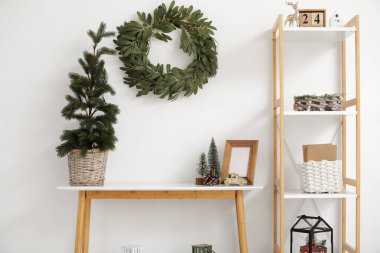 İçinde Noel çelengi, masa ve raf ünitesi olan oturma odası.