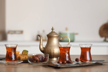 Bir bardak lezzetli Türk çayı, çaydanlık ve mutfaktaki masada hurma.