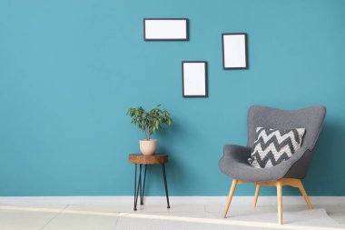 Mavi duvarda boş çerçeveler olan oturma odasının içi.