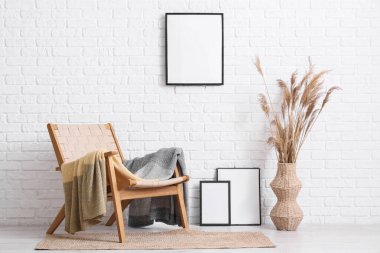 Odanın içindeki beyaz tuğla duvarın yanında boş çerçeve ve koltuk.