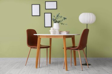 Masası, sandalyeleri ve vazoda okaliptüs dalları olan şık bir yemek odası.