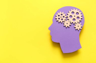 Sarı arka planda vitesleri olan kağıt insan kafası. Dünya Akıl Sağlığı Günü