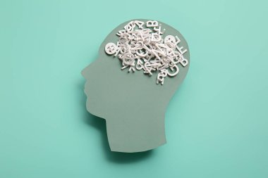 Turkuaz arka planda şifreli harflerle insan kafası. Dünya Akıl Sağlığı Günü