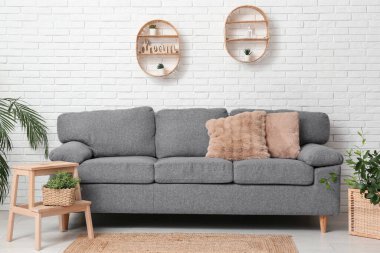 Gri kanepeli ve sepetli ev bitkileriyle şık bir oturma odası.